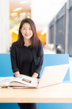 Oturmuş bir dizüstü bilgisayar, bir kitap Asya kolej öğrenci