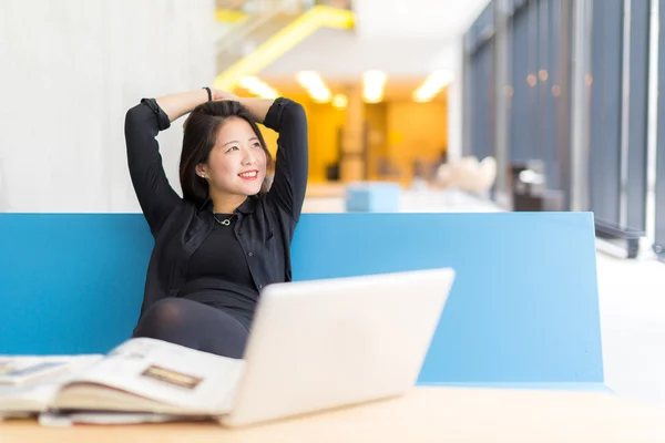 Oturmuş bir dizüstü bilgisayar, bir kitap Asya kolej öğrenci