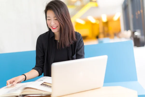 Oturmuş bir dizüstü bilgisayar, bir kitap Asya kolej öğrenci