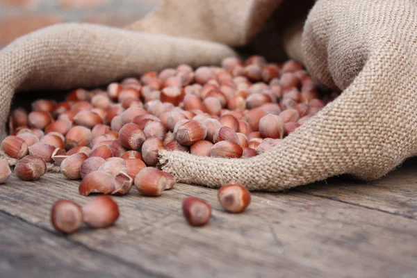 Hazelnut.Hazelnut gemorst uit de zak op een houten tafel — Stockfoto