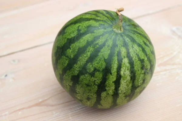 Grün gestreifte Wassermelone auf Holzplanken Hintergrund. — Stockfoto