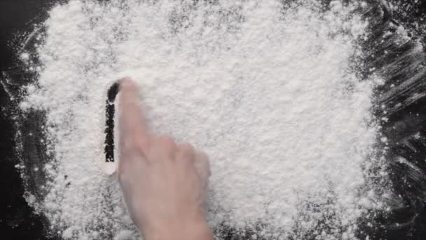 A hand writing on white flour — Stock Video