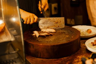 Bir şefin mükemmel kavrulmuş domuz rostosunu dilimlediği dinamik an (Siu Yuk)