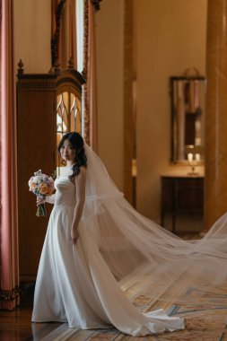 Lüks, klasik iç mimarisi olan zarif, beyaz elbiseli güzel bir Asyalı gelin. Yüksek kalite fotoğraf