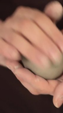 Seramik atölyedeki kil topunu şekillendiren ellerin yakın çekimi, el yapımı çömlekçiliğin işçiliğini, dokunulabilir sürecini ve sanatsal yaratıcılığını vurguluyor. Yüksek kalite 4k görüntü