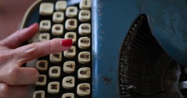  Kadın eski mavi bir daktiloyla yazı yazıyor. Mektuplar anahtarlara kazınmış. Çerçevesinde kırmızı tırnak askılı bir kızın elleri var. Bir kitap yazıyor. İçeride. Yüksek kalite 4k görüntü