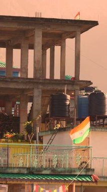 Hindistan 'ın ulusal bayrağı yumuşak sabah sisinde dalgalanan, günlük yaşamı, gururu ve huzurlu kırsal atmosferi sembolize eden Hindistan' daki köy evlerinin çatılarına su depolama tankları yerleştirildi. Yüksek kalite 4k görüntü