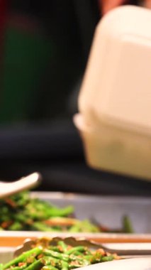 Yoğun bir gıda pazarında bulunan sebzeler, balıklar ve et yemekleri de dahil olmak üzere Asya mutfağının geniş bir yelpazesi, uygun paket servis ve yüksek kaliteli 4K görüntüler için tek kullanımlık konteynırlara servis edilmektedir.