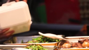 Yoğun bir gıda pazarında bulunan sebzeler, balıklar ve et yemekleri de dahil olmak üzere Asya mutfağının geniş bir yelpazesi, uygun paket servis ve yüksek kaliteli 4K görüntüler için tek kullanımlık konteynırlara servis edilmektedir.