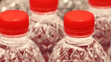 Rafta veya konveyör hattında kırmızı kapaklı plastik su şişeleri. Yüksek kalite 4k görüntü