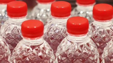 Rafta ya da konveyör ekranında kırmızı kapaklı şeffaf plastik su şişelerinin yakın çekimi. Yüksek kalite 4k görüntü