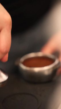 Barista, portafilter ve kurcalayıcıyla kahve hazırlıyor. Portafilter 'ı kahveyle doldurmak ve hatta kahve dükkanında kurcalayıcı kullanarak baskı uygulamak. Yüksek kalite 4k görüntü