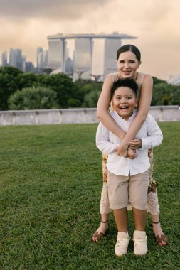 Marina Körfezi siluetiyle Singapur 'da poz veren mutlu uluslararası anne ve oğul. Yüksek kalite fotoğraf