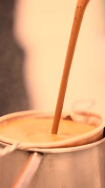 Sütlü ya da tereyağlı sıcak Asya çayı süzgeçle fincana dökülüyor.