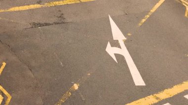 Asfalttaki beyaz yol ok işaretleri izin verilen yönü gösterir: düz veya sağa dönüş, trafik rehberliğini, sokak altyapısını, kentsel yol konseptini, güvenli sürüş 4K görüntü kalitesini gösterir