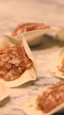 Hamur ve etten yapılan hamur köfteleri mermer bir masanın üzerinde hazır ve yemek projeleri teması için mükemmel geleneksel bir dünya mutfağı tarzını sunmaya hazır. Yüksek kalite 4k görüntü