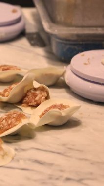 Hamur ve etten yapılan hamur köfteleri mermer bir masanın üzerinde hazır ve yemek projeleri teması için mükemmel geleneksel bir dünya mutfağı tarzını sunmaya hazır. Yüksek kalite 4k görüntü