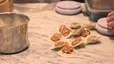 Hamur ve etten yapılan hamur köfteleri mermer bir masanın üzerinde hazır ve yemek projeleri teması için mükemmel geleneksel bir dünya mutfağı tarzını sunmaya hazır. Yüksek kalite 4k görüntü