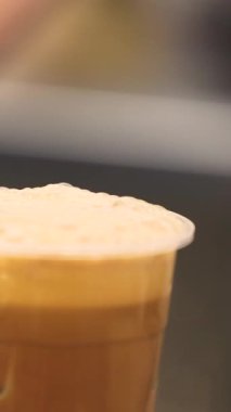 Balonlu çay kahve konseptinin üzerinde köpüğü ve modern tüketimde tek kullanımlık fincanların ekolojik endişelerini gösteren plastik bir kullan-at bardakta sıcak çay içeceğinin yakınlaştırılması. Yüksek kalite 4k görüntü