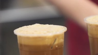 Balonlu çay kahve konseptinin üzerinde köpüğü ve modern tüketimde tek kullanımlık fincanların ekolojik endişelerini gösteren plastik bir kullan-at bardakta sıcak çay içeceğinin yakınlaştırılması. Yüksek kalite 4k görüntü