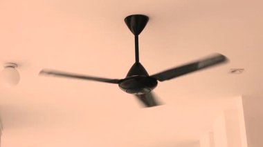 Siyah tavan vantilatörü, ev içinde yavaşça dönüyor ve içeride soğutma sağlıyor. Yüksek kalite 4k görüntü