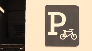 Siyah dikdörtgen üzerinde beyaz P ve bisiklet simgesi var.