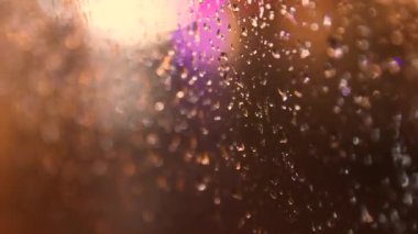 Sıcak romantik yağmurlu atmosferde yağmur damlalarıyla cam boyunca geri çekilen kamera. Yüksek kalite 4k görüntü