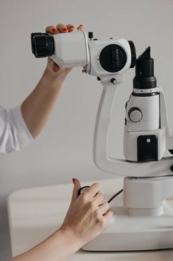 Klinikteki göz muayenesi sırasında göz mikroskobunu ayarlayan eller. Yüksek kalite fotoğraf