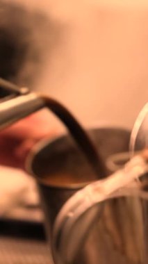 Büyük metal bir bardaktan geleneksel bir Asya su ısıtıcısına akan kalın bir sokak kahvesi. Bu dökme tekniği Asya kahve ve çay kültüründe popüler olan birayı serinletir ve güçlendirir. Yüksek kalite 4k görüntü