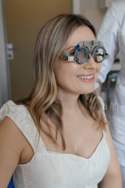 Göz doktorundaki beyaz kadın görüş kontrolü sırasında optik çerçeve takıyor. Yüksek kalite fotoğraf