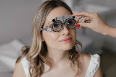 Göz doktorundaki beyaz kadın görüş kontrolü sırasında optik çerçeve takıyor. Yüksek kalite fotoğraf
