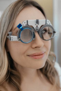 Göz doktorundaki beyaz kadın görüş kontrolü sırasında optik çerçeve takıyor. Yüksek kalite fotoğraf