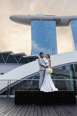 Gelin ve damat, Singapur şehrinin arka planına karşı. Güneşin doğuşu düğün fotoğrafı. - Evet. Yüksek kalite fotoğraf