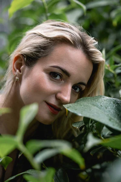 Yeşil yapraklarla çevrili güzel sarışın bir kızın yakın plan portresi. O modern bir saç stili giyiyor. Kuaförler ve kuaförler için. Konsept doğal güzellik. Yüksek kalite fotoğraf