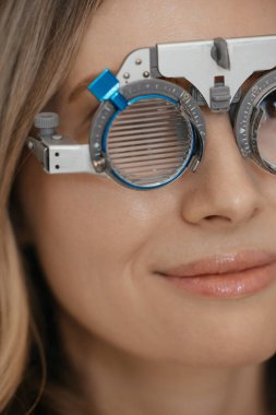 Göz doktorundaki beyaz kadın görüş kontrolü sırasında optik çerçeve takıyor. Yüksek kalite fotoğraf