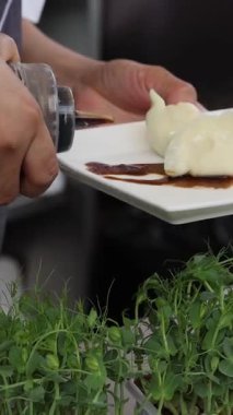 Bir şef geleneksel Çin böreklerinin üzerine yemek tezgahı ya da yiyecek pazarında sos döker. Yüksek kalite 4k görüntü