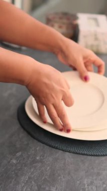 Eller lüks restoran masasına temiz beyaz tabaklar koyuyor.