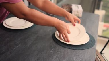 Eller lüks restoran masasına temiz beyaz tabaklar koyuyor.