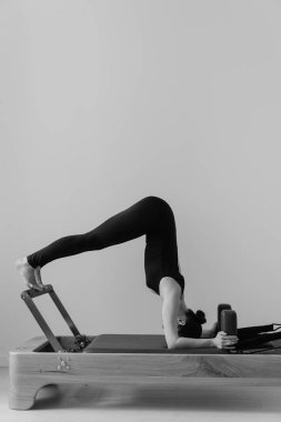 Pilates makinesinde eğitim gören bir kadının siyah beyaz fotoğrafı. Yüksek kalite fotoğraf
