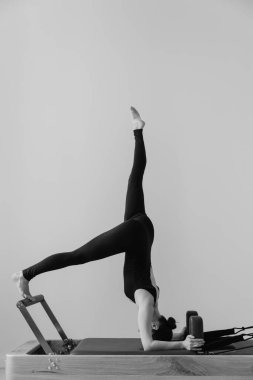 Pilates makinesinde eğitim gören bir kadının siyah beyaz fotoğrafı. Yüksek kalite fotoğraf