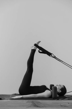 Pilates makinesinde eğitim gören bir kadının siyah beyaz fotoğrafı. Yüksek kalite fotoğraf