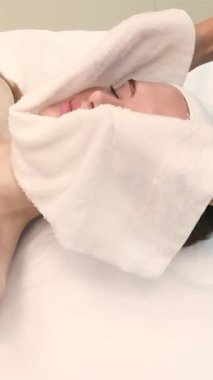 Cilt bakımı sırasında güzel bir kadının yüzünü temizleyen kozmetikçi.