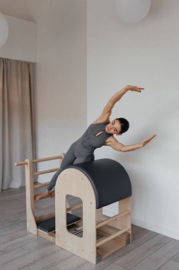 Atletik esmer kadınla pilates merdiveni makinesi eğitimi.