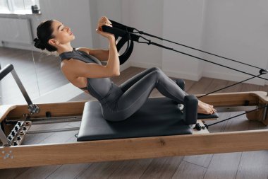 Makinedeki çok yönlü egzersizleri gösteren pilates reformatörü eğitimi