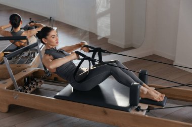 Makinedeki çok yönlü egzersizleri gösteren pilates reformatörü eğitimi
