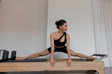 Pilates yenilikçisi, siyah kıyafetli atletik bir kadının ayakta kalma egzersizi.