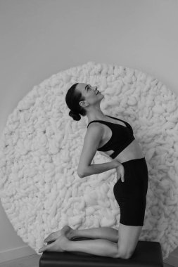 Stüdyonun içinde yoga yapan bir kadının siyah beyaz fotoğrafı.