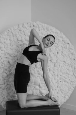 Stüdyonun içinde yoga yapan bir kadının siyah beyaz fotoğrafı.