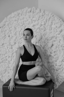 Stüdyonun içinde yoga yapan bir kadının siyah beyaz fotoğrafı.