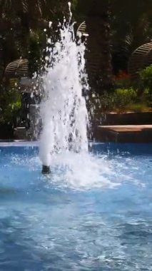 Tek jet fıskiyesi açık havuzdan su fışkırtıyor.